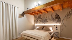 A bedroom with a bed, a wall-mounted TV, a ceiling light, and a decorative leaf mural. - Marietta Home With Lake View by Wonderful Italy (Gardone Riviera)