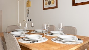 A dining table set with plates, wine glasses, and cutlery, surrounded by chairs. - Marietta Home With Lake View by Wonderful Italy (Gardone Riviera)