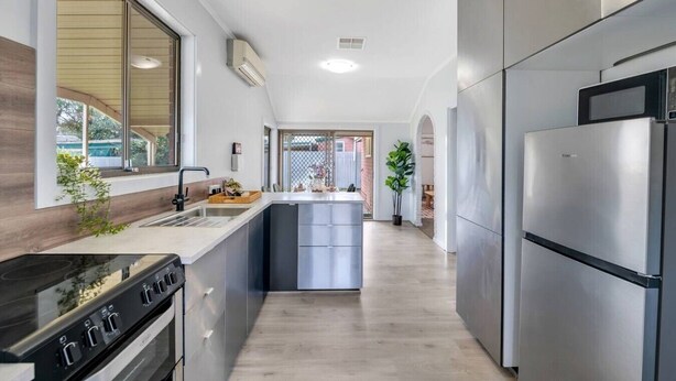 Een moderne keuken met een centraal eiland, roestvrijstalen apparatuur en een groot raam.