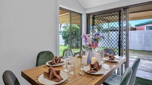 Een eettafel gedekt voor vier personen, met een bloevas, kaarsen en keurig gevouwen servetten.