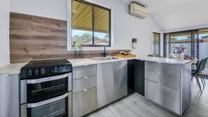 Een moderne keuken met een ingebouwde oven, een groot raam en een eetgedeelte met uitzicht.