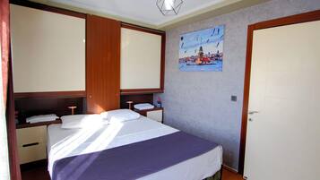 Un dormitorio con una cama, una mesita de noche, un estante en la pared, una puerta y un cuadro.