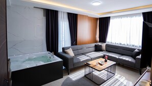 Una sala moderna con un sofá modular, un revestimiento de pared de madera, un ventanal con cortinas, un jacuzzi integrado y una mesa de centro.