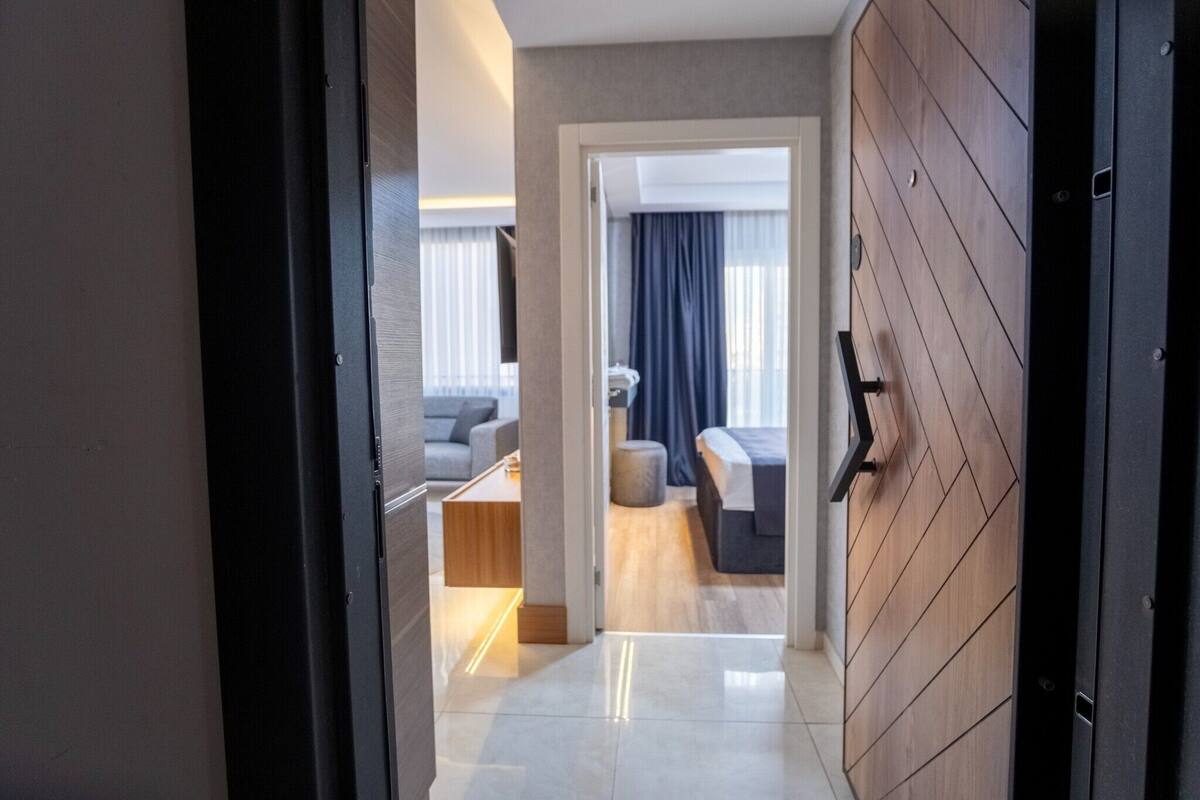 A modern hotel room with a wooden wall, a bed, a sofa, and a small table.