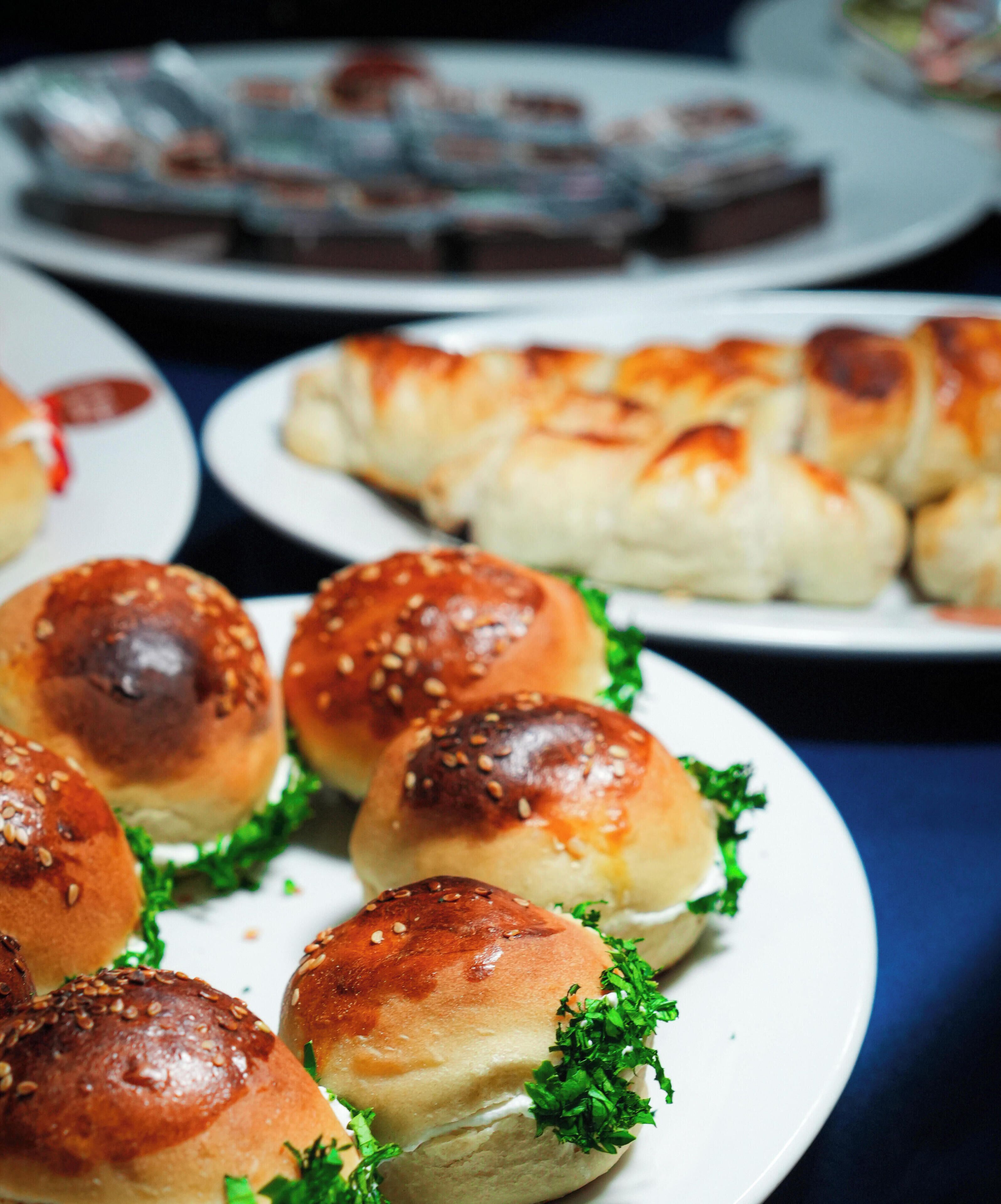 Une table où sont présentés divers aliments, notamment des petits pains et des pâtisseries.
