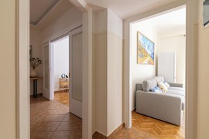 A hallway with a grey sofa and a painting on the wall. - Family Apartment | 50m from Acropolis Museum | 2BR 2BA (Athina)