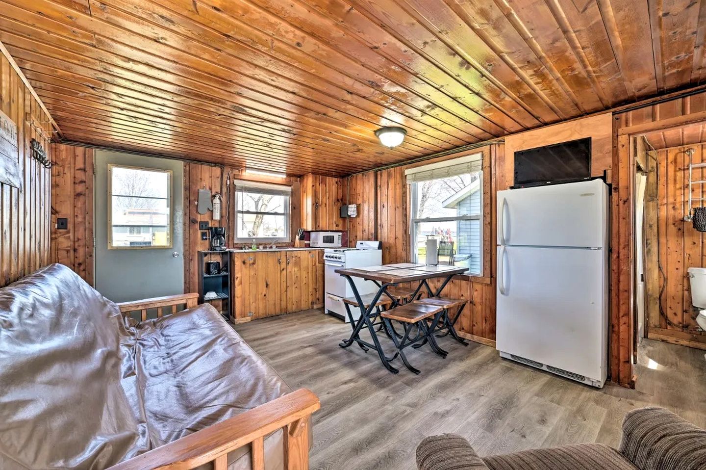 A cabin with a wooden interior, a kitchenette, a dining table, and a sofa.