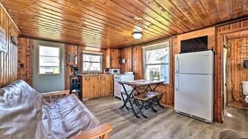 A cabin with a wooden interior, a kitchenette, a dining table, and a sofa.