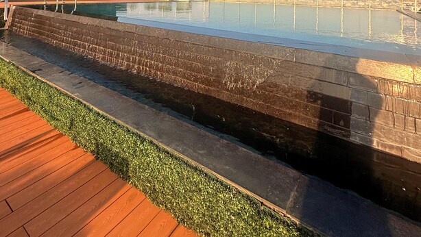 Ein Pool auf dem Dach mit freiem Blick auf die Stadtlandschaft, einer Holzterrasse und einer Steinmauer.