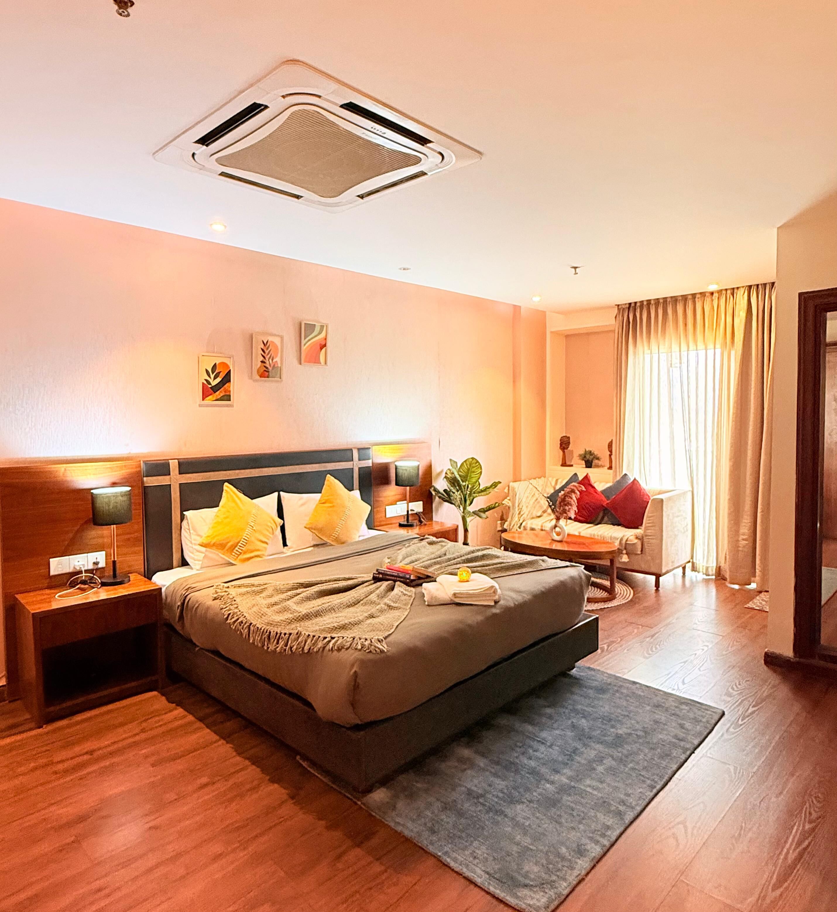 A hotel room with a bed, bedside tables, a desk, a chair, and a window with curtains.
