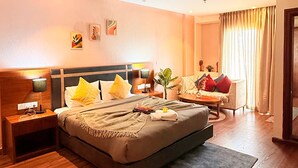 Ein Hotelzimmer mit Bett, Nachttischen, Schreibtisch, Stuhl und einem Fenster mit Vorhängen.