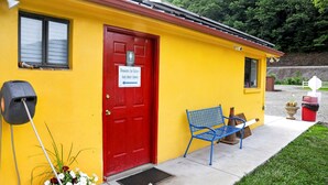 A yellow building with a red door, a blue bench, and a sign indicating showers for tubers last door down. - Safari Tent Retreat with Riverfront Deck and Nature Stay in Blacksburg, Virginia (Blacksburg)