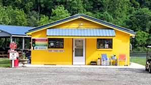 A yellow building with a blue roof, a 'RENT TUBES HERE' sign, a stop sign, and a parking sign. - Safari Tent Retreat with Riverfront Deck and Nature Stay in Blacksburg, Virginia (Blacksburg)