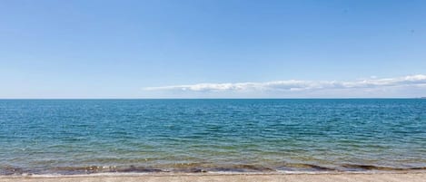 A beach with clear blue water and a sandy shore.