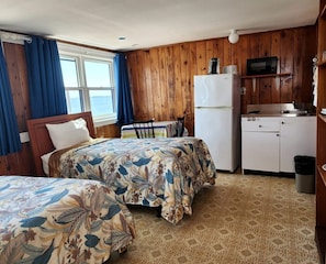 Ein Zimmer mit zwei Betten, einer kleinen Küchenzeile und Meerblick.
