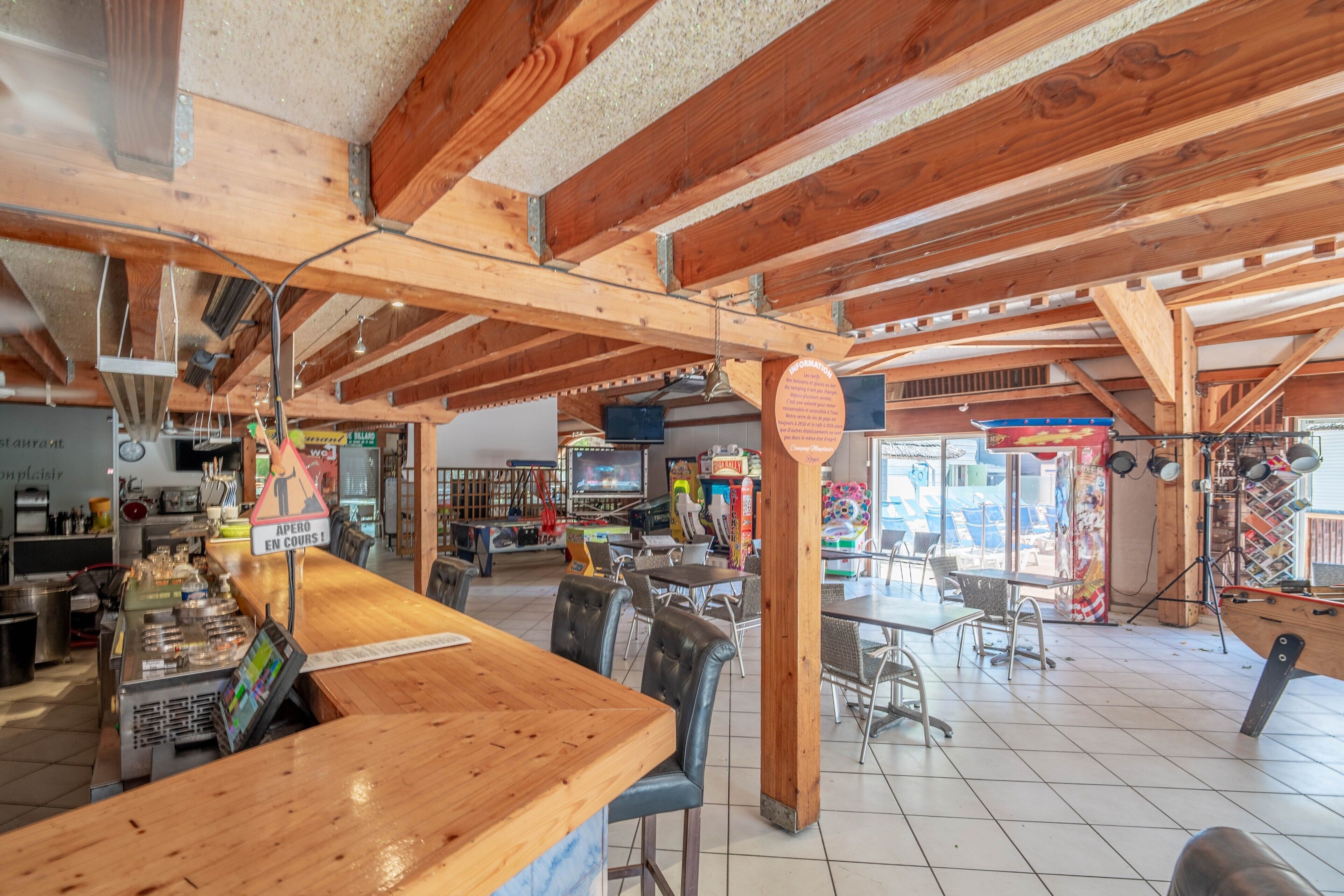 Ein geräumiges Restaurant mit Holzbalken, einer Bar und unterschiedlichen Sitzgelegenheiten.