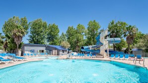 Una piscina con sillas azules, un tobogán y un edificio con techo azul.