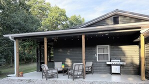 A covered patio with outdoor seating and a grill area.