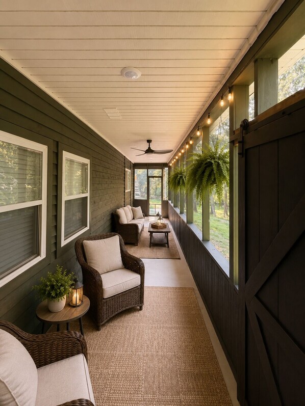 Eine überdachte Veranda mit Korbmöbeln, Deckenventilator und Lichterketten.