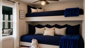 A bunk bed with a ceiling fan, a plush unicorn toy, and a motivational poster.
