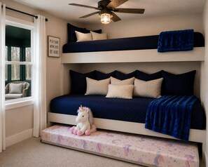 A bunk bed with a ceiling fan, a plush unicorn toy, and a motivational poster.
