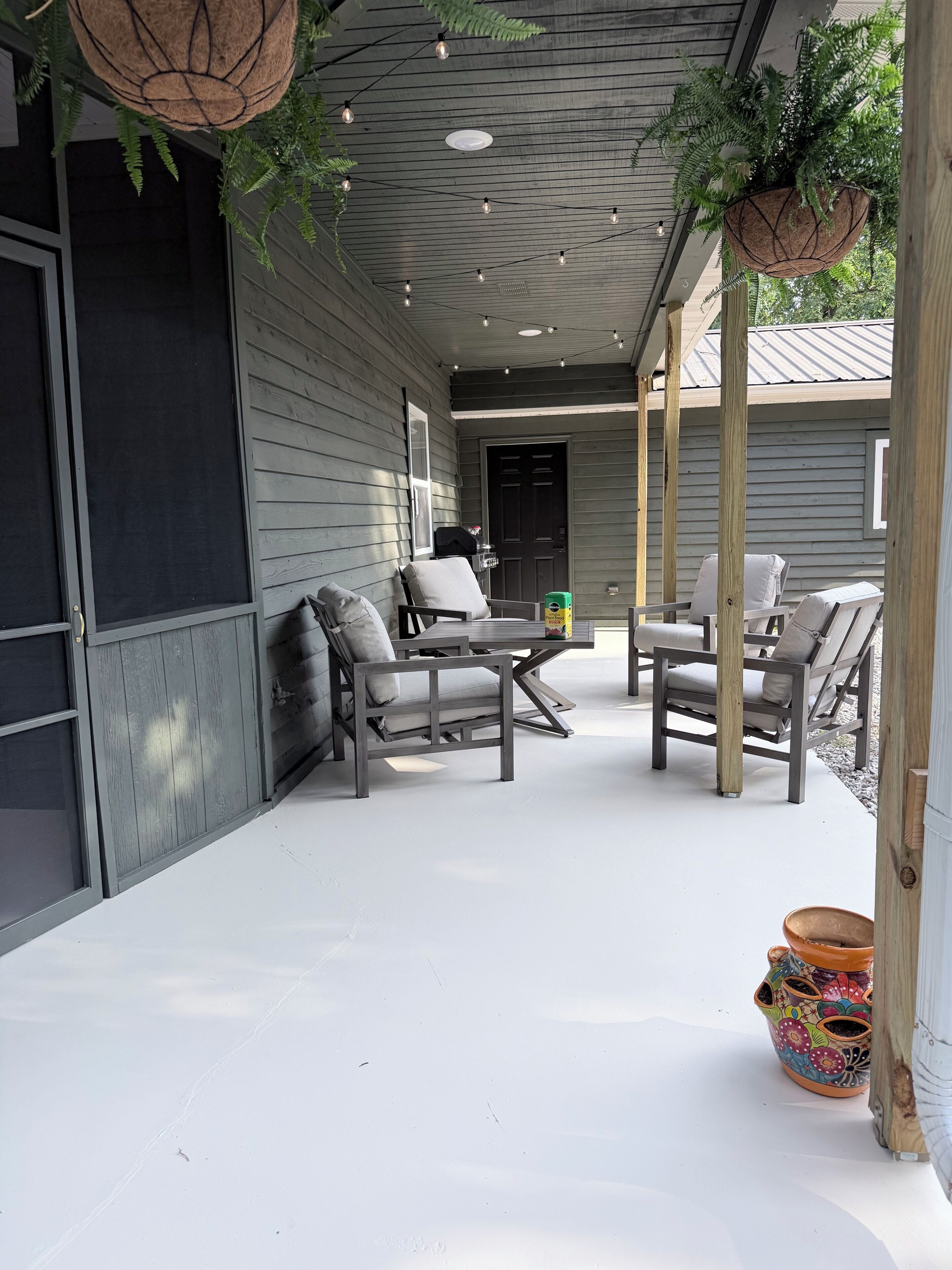Un espace extérieur aménagé en patio, avec des sièges, une porte et un pot de fleurs.