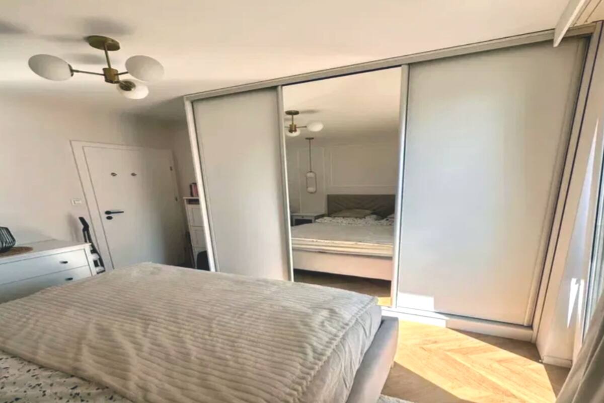 Un dormitorio con cama, cómoda, ventilador de techo y puerta corrediza que da a otra habitación.