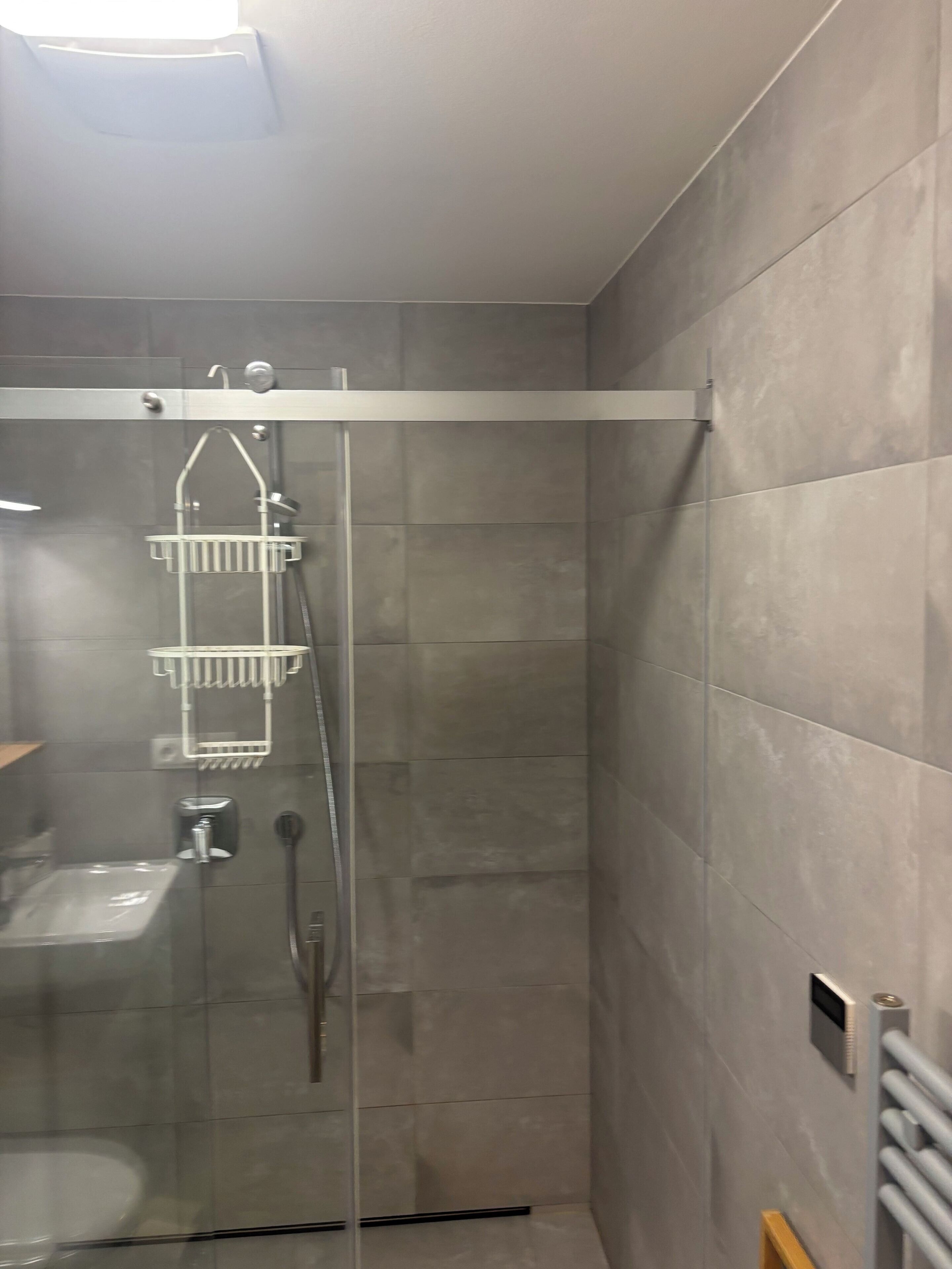 Un baño moderno con ducha de mampara de vidrio, inodoro y lavamanos.