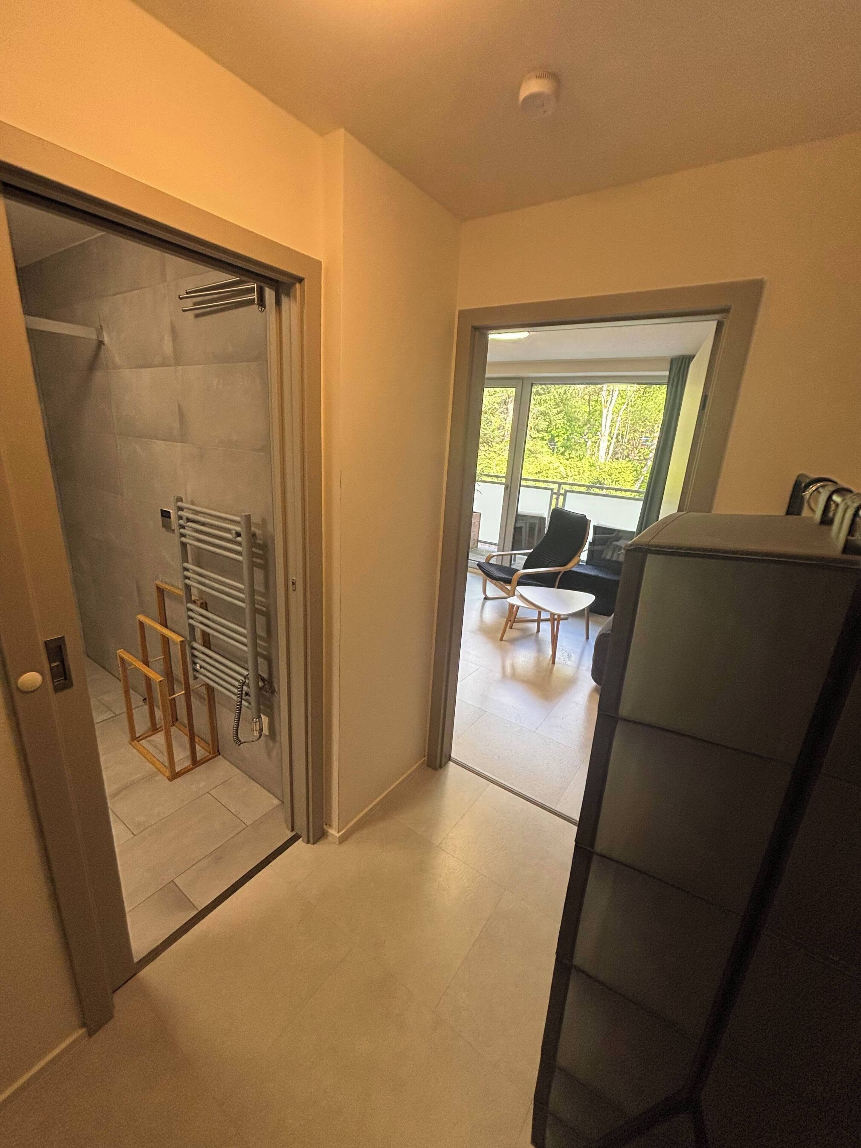 Ein modernes Interieur mit Glastür zum Balkon, einer Sitzecke mit Tisch und Stühlen sowie einem an der Wand montierten Thermostat.