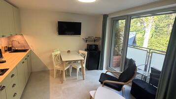 A modern kitchen with a dining area, a flat-screen TV, and a balcony with a view.