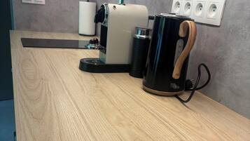 A wooden counter with a coffee maker, a kettle, and a power strip with four sockets.