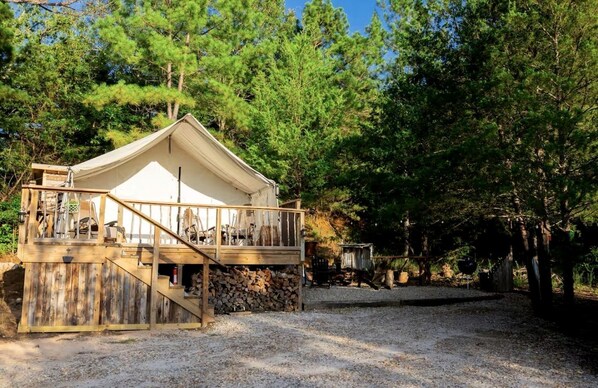 A cabin with a balcony, a staircase, and a gravel ground.
