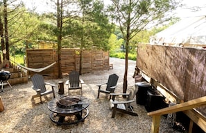 A patio with outdoor seating, a fire pit, and a rustic wooden structure.