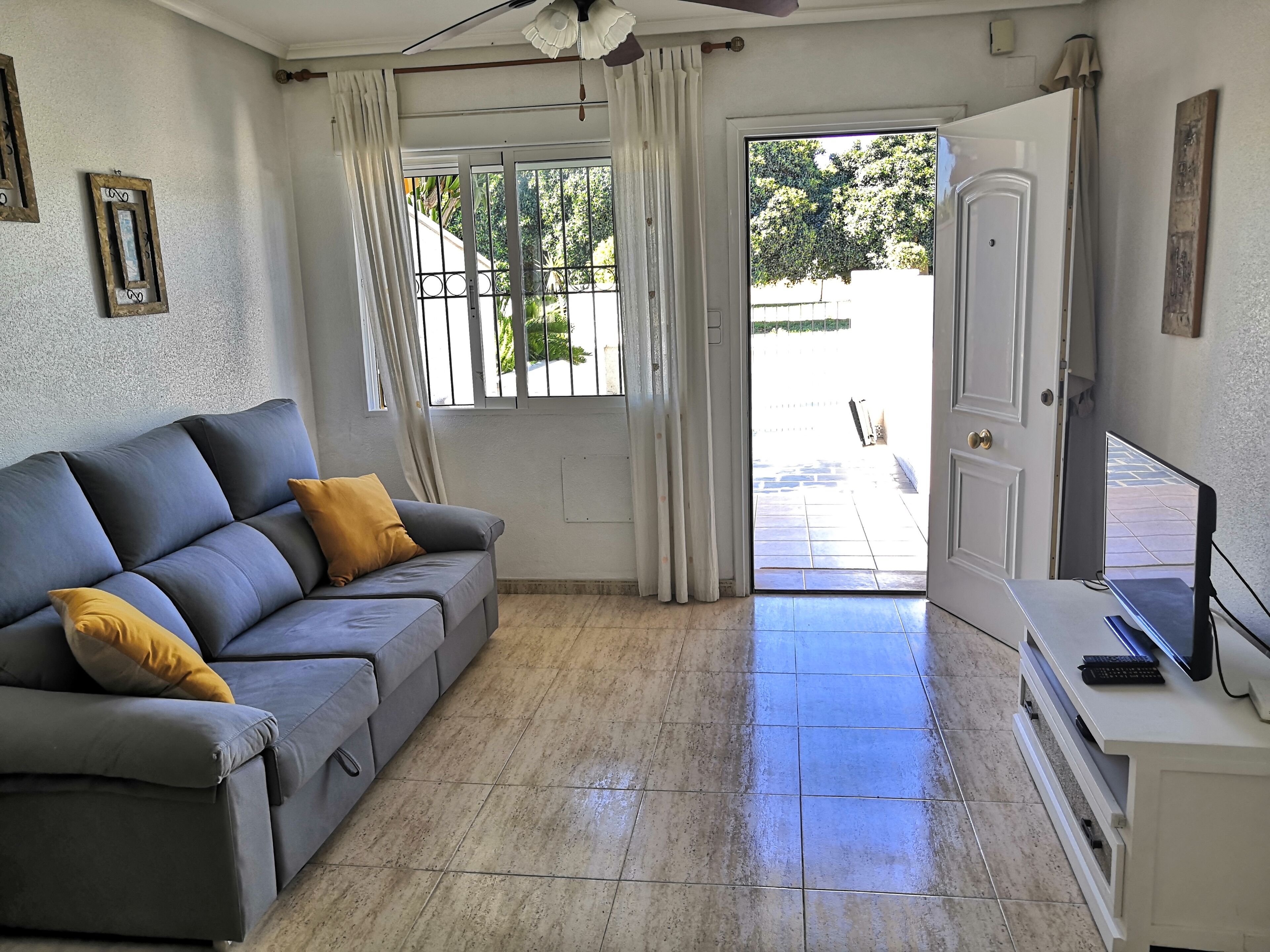 Una sala de estar con un sofá, un televisor y una puerta que da al exterior.