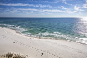 Ein Strand mit blauem Himmel, ruhiger See und sandigem Ufer.