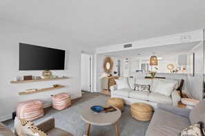 Ein modernes Wohnzimmer mit einem Flachbildfernseher, einem weißen Sofa und einem Couchtisch.
