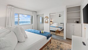 Ett hotellrum med en säng, ett skrivbord, en garderob och utsikt över havet.
