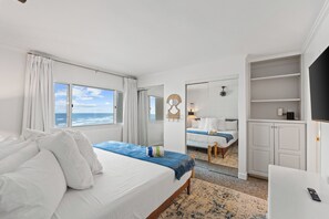 Ein Hotelzimmer mit Bett, Schreibtisch, Kleiderschrank und Meerblick.