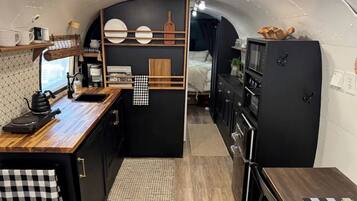 Une petite cuisine équipée avec un plan de travail en bois, un évier, une petite cuisinière et un réfrigérateur.