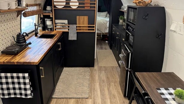 A compact kitchenette with a wooden countertop, a sink, a small stove, and a refrigerator. - Luxurious Remodeled Airstream with Wraparound Deck and Spa near Honey Grove, Texas (Honey Grove)