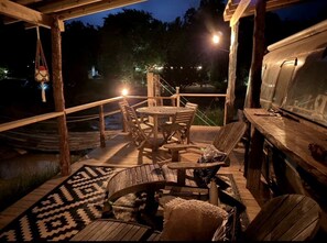 Eine Terrasse im Freien mit Holzmöbeln, einem Grill und einem gemusterten Teppich.