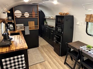 Eine kleine Küche mit einer Holz Arbeitsplatte, schwarzen Schränken und einem schwarzen Kühlschrank.