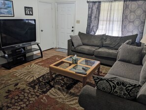 A living room with a television, a sofa, a coffee table, and a patterned rug. - 3-bedroom house centrally located in Pensacola (Pensacola)