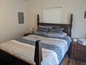 A bedroom with a four-poster bed, a bedside table with a lamp, a dresser, and a window with blinds. - 3-bedroom house centrally located in Pensacola (Pensacola)