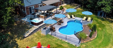 Een achtertuin met een zwembad, buitenmeubels en een jacuzzi.