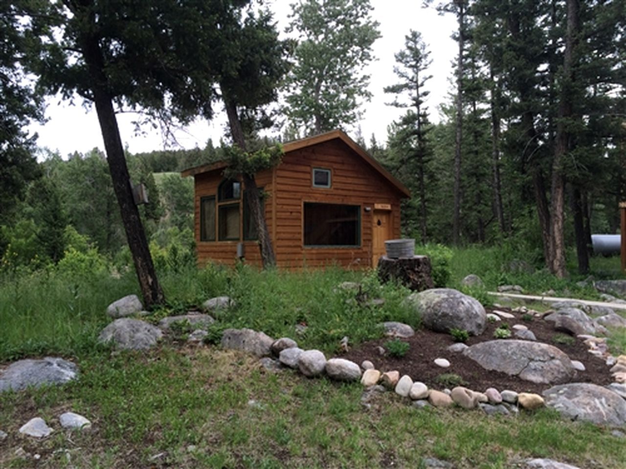 A small wooden cabin surrounded by rocks and trees.