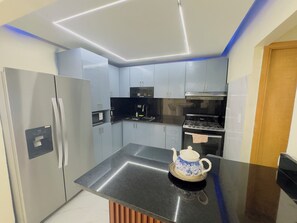 A modern kitchen with stainless steel appliances, a water dispenser, and a decorative teapot on the counter.