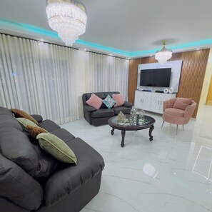 A modern living room with a sofa, armchair, coffee table, TV, and decorative items.