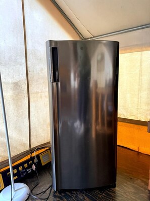 A stainless steel refrigerator in a room with a tiled wall and a window.