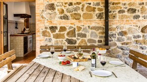 An outdoor dining area with stone walls, wooden benches, and a table set for a meal. - Vrbo Property (Radicofani)